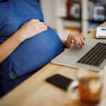 Pregnant employee impacted by Pregnant Worker Fairness Act sitting at desk